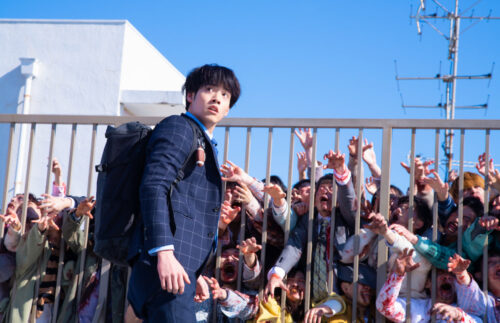 Zom 100 Bucket List promo image of character in front of hoard of Zombies (Source: Netflix)