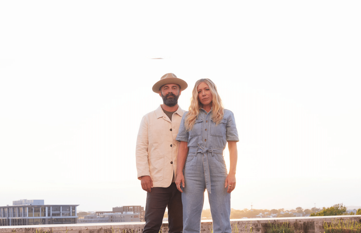 Drew and Ellie Holcomb standing together outside in promo photo for their album "Memory Bank"